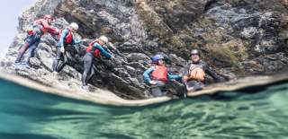 people enjoying coasteering wearing protective suits and helmets