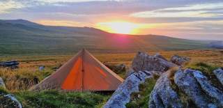 tent pitched at Dartmoor National Park with a view and sunset in a background