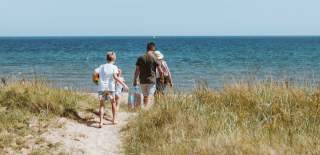 Family walking towards the sea through sand dunes at Spurn