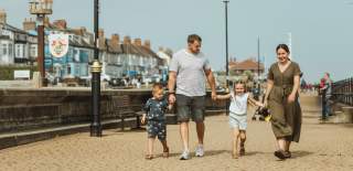 A family walking hand-in-hand along Hornsea's promenade