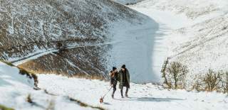 A couple walking their dog through a snow covered Yorkshire Wolds in East Yorkshire