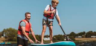 Father helping son to paddle board at Allerthorpe Lakeland Park