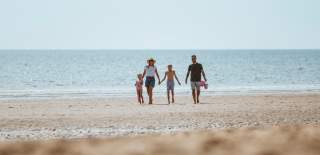 A family of four walking barefoot in the distance on the beach in Bridlington, East Yorkshire