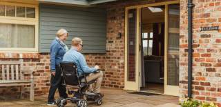 A couple entering Broadgate farm cottages, one person is walking and one is in a motorised wheelchair
