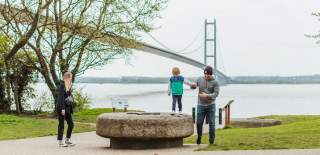 A family playing with the Humber Bridge in the background