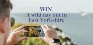 A man taking a photo at Bempton Cliffs with the wording win a wild day out in East Yorkshire