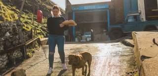 A woman with her dog walking in front of The Boathouse in Flamborough carrying a seafood platter