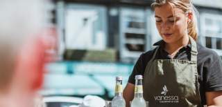A member of staff from Vanessa Cafe and Delicatessen in Beverley taking some drinks to customers sat outside