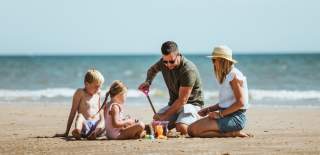 A couple and their two young children building sandcastles on the beach in Bridlington, East Yorkshire