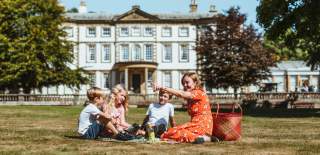 Family sat on the grass with Sewerby Hall in the background