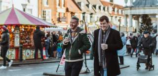 A couple walking through saturday market, Beverley, carrying hot chocolates at the Beverley Festival of Christmas