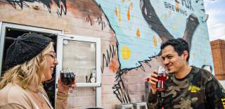exterior of social fox brewery with large fox mural and man and woman drinking beer
