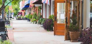 Charming sidewalk in Norcross downtown with planters, benches, and a welcoming shop entrance along a lively, walkable streetscape.
