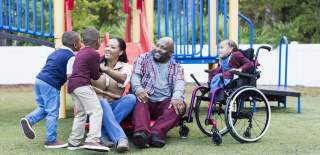 Kids, mother, father and wheelchair-bound child at an outdoor playground