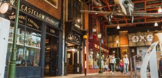 The Streetlife Museum in Hull. A man and a woman with young children walk through the museum which is a mock up of a victorian street with cobbled pavements and old style shop fronts. A propeller plane hangs from the ceiling.