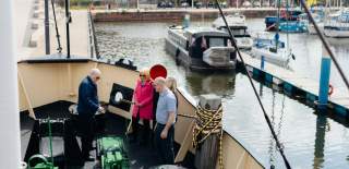 Visitors exploring the deck of a Spurn Lightship at Hull Marina, with moored boats and waterfront buildings in the background during a guided tour.