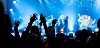 A crowd of people hold their arms in the air at a concert.