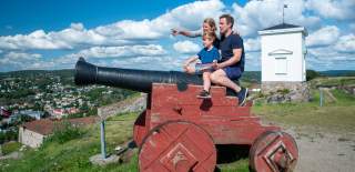 Familie som sitter på en kanon på Fredriksten festning i Halden.
