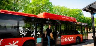 Ung mann går av en rød Østfold-buss