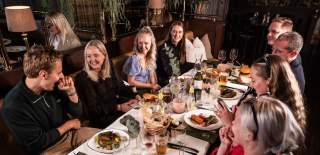 En gjeng med glade mennesker som sitter rundt et bord på STAY i Sarpsborg. Foto.