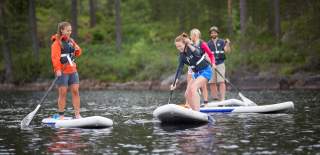 En gruppe mennesker har det gøy på SUP-brett i Rømskog.