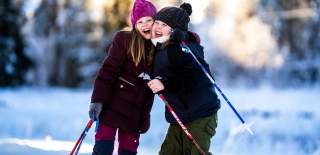 Two happy girls on a ski trip stop and giving each other a hug