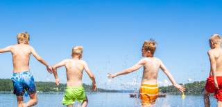 4 guys in colorful shorts running into the water