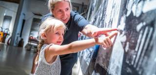 Mor og barn studerer bildene på veggen på kanalmuseet