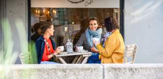 Venninnegjengen sitter sammen på kafé