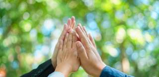 Tre hender som gir hverandre "high five"