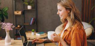 Ung kvinne sitter smilende foran en laptop