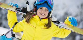 Jente i gul skijakke som holder alpintski
