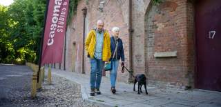 A couple with their black dog walking towards the entrance of Casemates Studios and Cafe