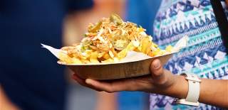 A close up shot of a tray piled with street food at an outdoor event