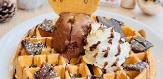 A waffle topped with ice cream and chocolate pieces and a Hooray's wafer