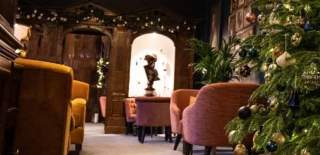 An oak panelled lounge with a Christmas tree in the foregound