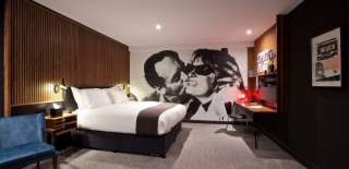 A contemporary hotel bedroom with a full wall covered by a black and white mural