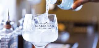 A close up shot of a glass of Shakespeare Distillery gin with a tonic being poured into the glass