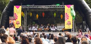 Back of crowd watching Khan Brothers on a stage at Southampton Mela Festival outside in Hoglands Park on a sunny day