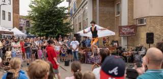 Man on unicycle juggling in front of large crowd