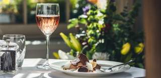 Fine dining plate of food next to a glass of wine on a table