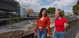 Two people walking at the top of the Esplanade looking at each other and talking and smiling