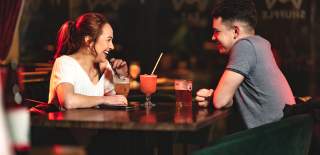 Young couple sitting at a table drinking cocktails at CRIB