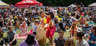 Crowd of people sat on the floor with two performancers dancing in the middle