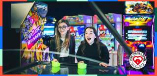Two girls playing air hockey at High Score Arcades