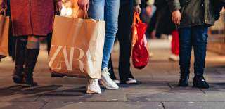 Shoppers on the high street holding shop branded bags