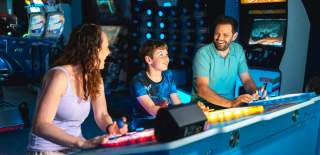 Family playing arcade game and smiling at each other