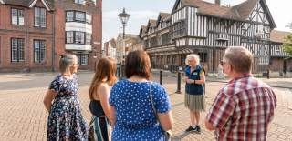 STGA Tour Guide with group outside Tudor House