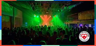 Lively crowd at a gig at The 1865 with green and orange stage spotlights