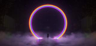 Image shows Lightport installation a large scale rainbow archway with a person standing underneath the centre of the archway